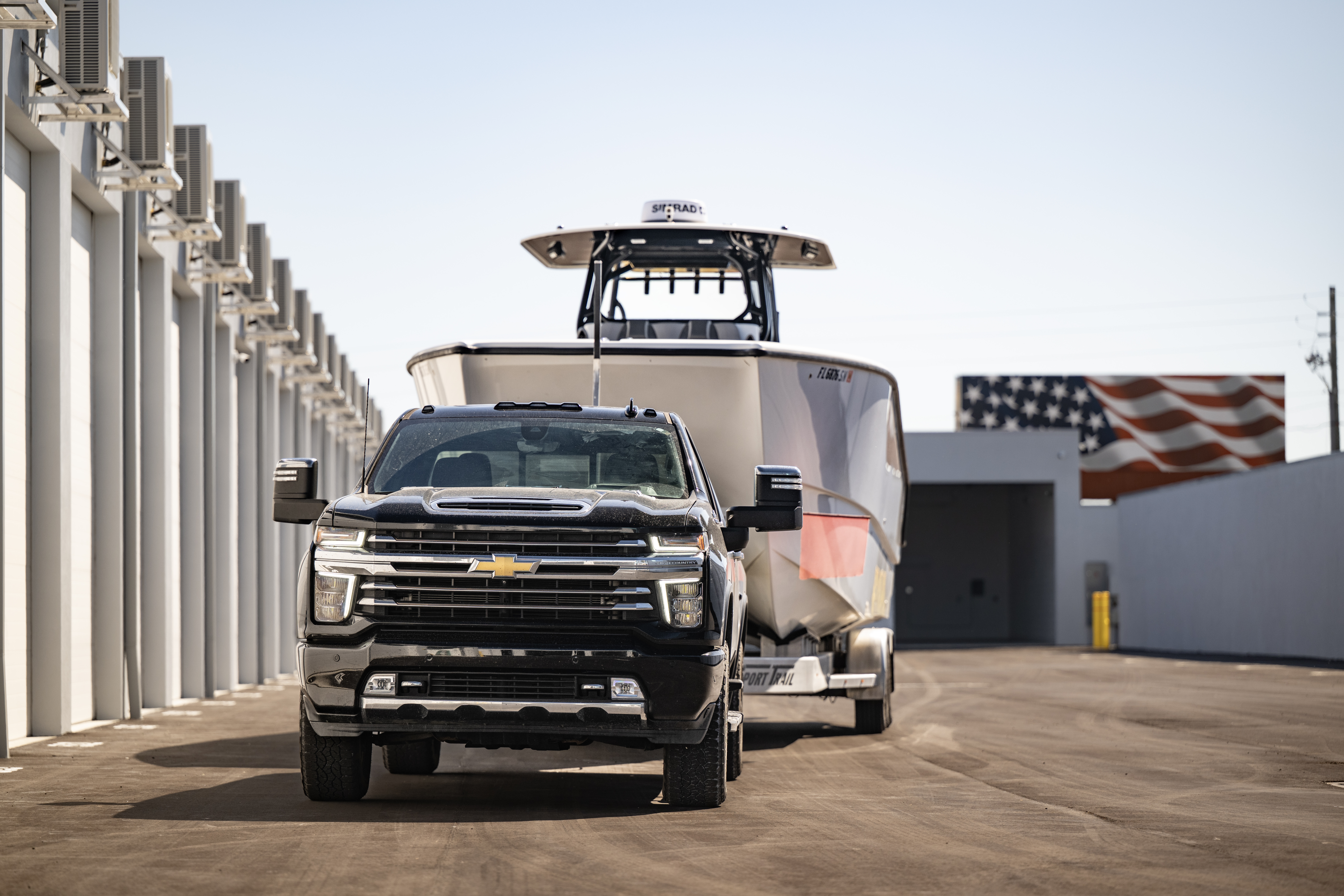 Truck towing a large center-console boat driving through wide paved aisles between private climate-controlled storage units at MetroMaxx RV & Boat Storage in Fort Myers, Florida